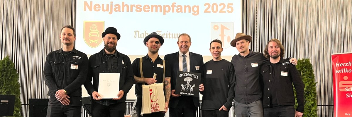 La photo montre les membres du groupe sur scène avec le maire Frühauf.