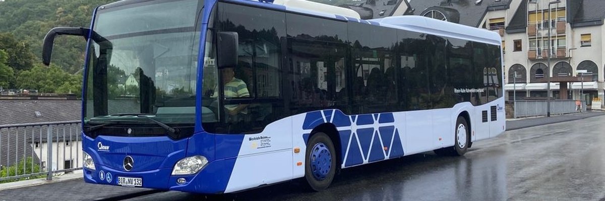 La photo montre un bus de ligne bleu qui s'arrête sur une route.