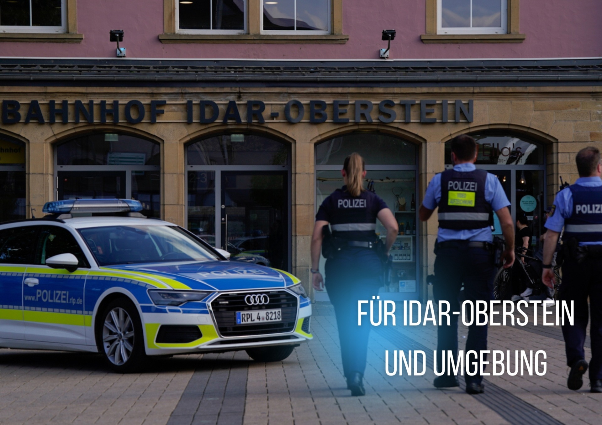 La photo montre trois policiers et une voiture de police devant la gare d'Idar-Oberstein.