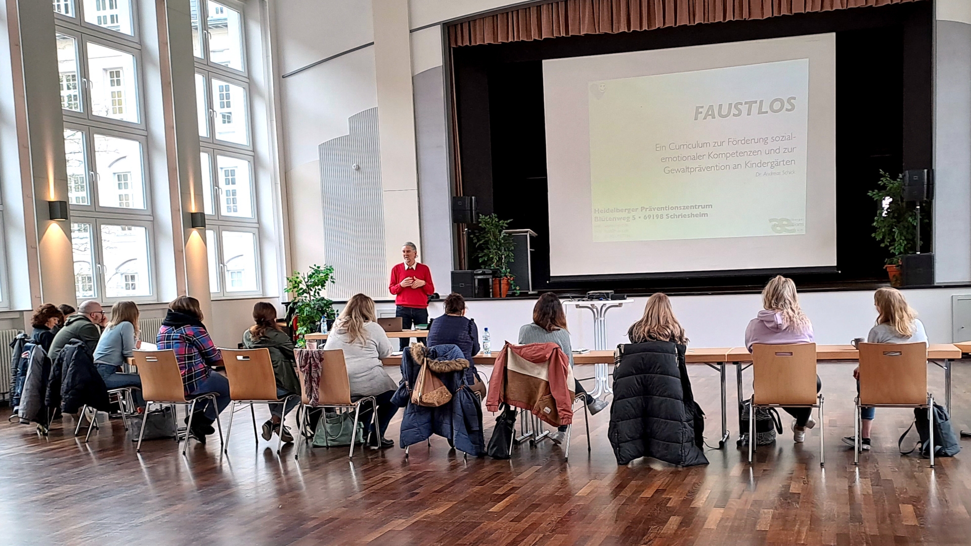 La photo montre les participantes à la formation, alignées sur une rangée de chaises devant le conférencier.