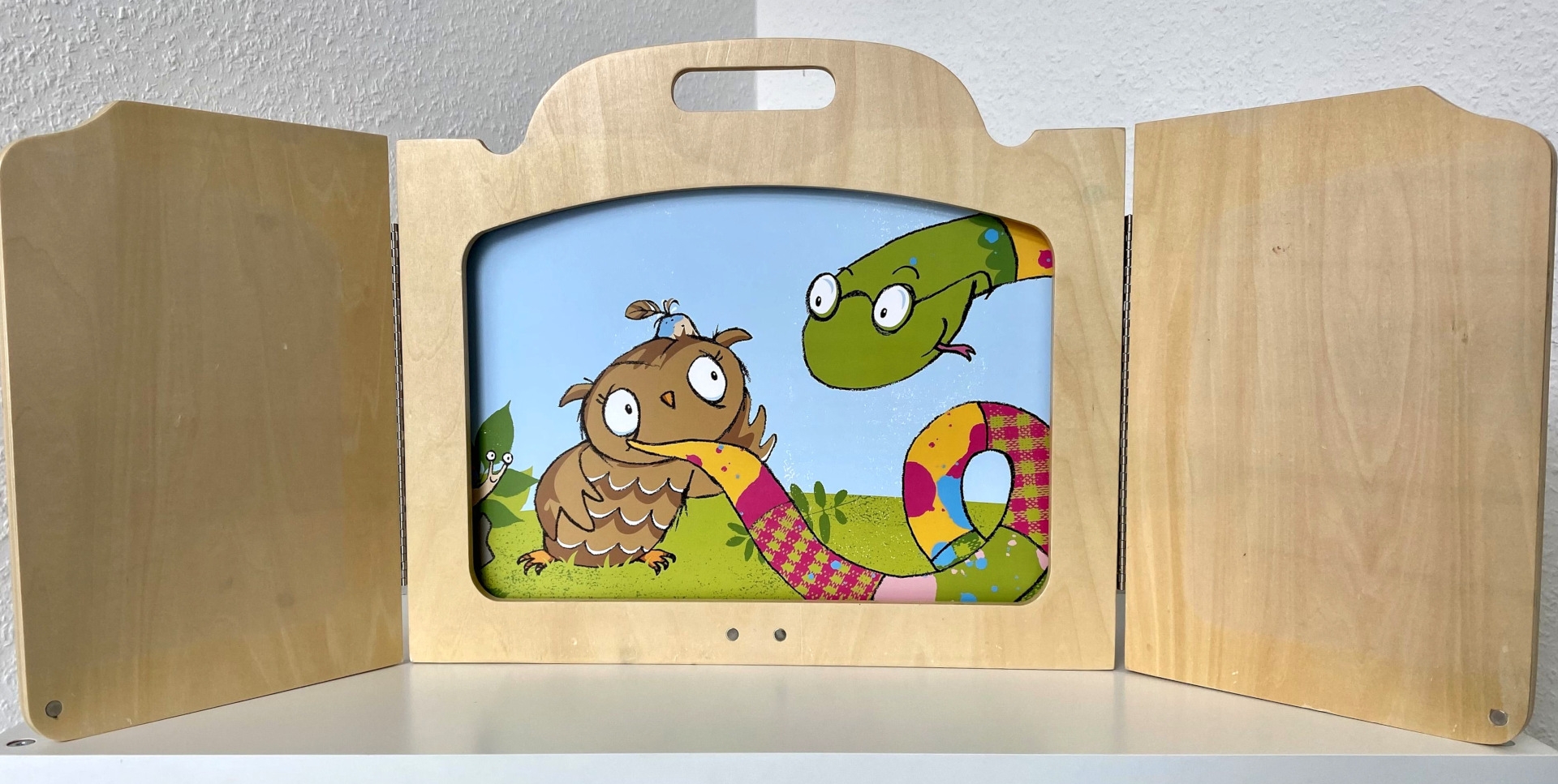 La photo montre un cadre en bois du Kamishibai avec une illustration colorée d'un hibou.