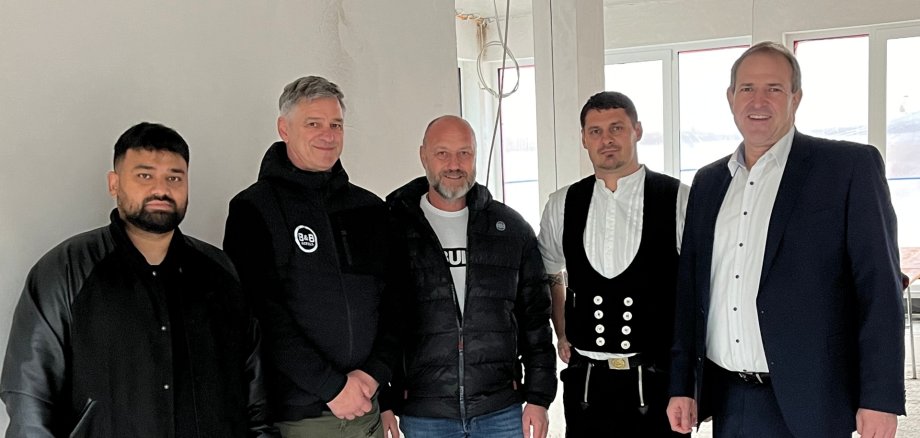 La photo montre les personnes mentionnées. Elles se tiennent côte à côte sur le chantier et regardent la caméra.