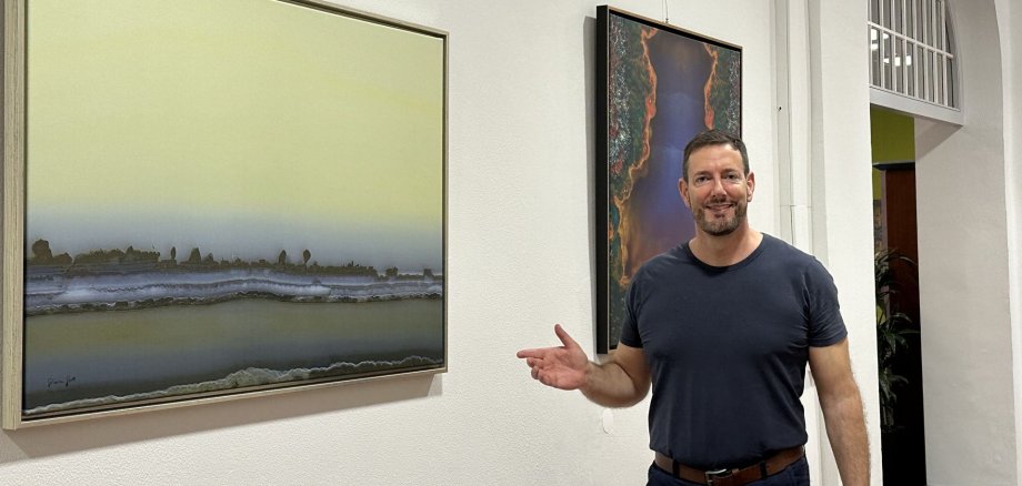 La photo montre Sebastian Stoll devant l'une de ses œuvres d'art.