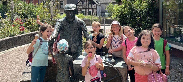 La photo montre les participants du rallye devant la statue de Bede Lorenzo dans la zone piétonne d'Oberstein.