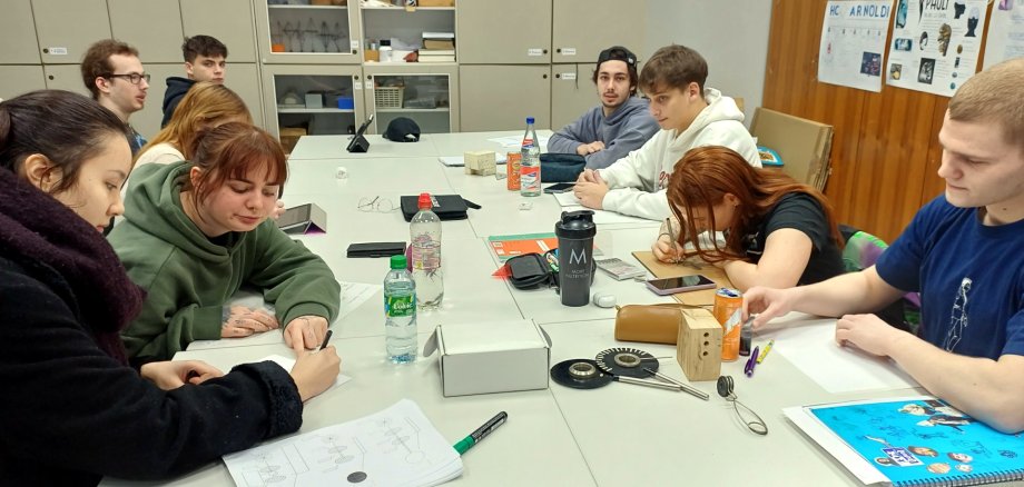 La photo montre de nouveaux élèves de la classe spécialisée. Ils sont assis à des tables d'école disposées en carré et préparent l'exposition.