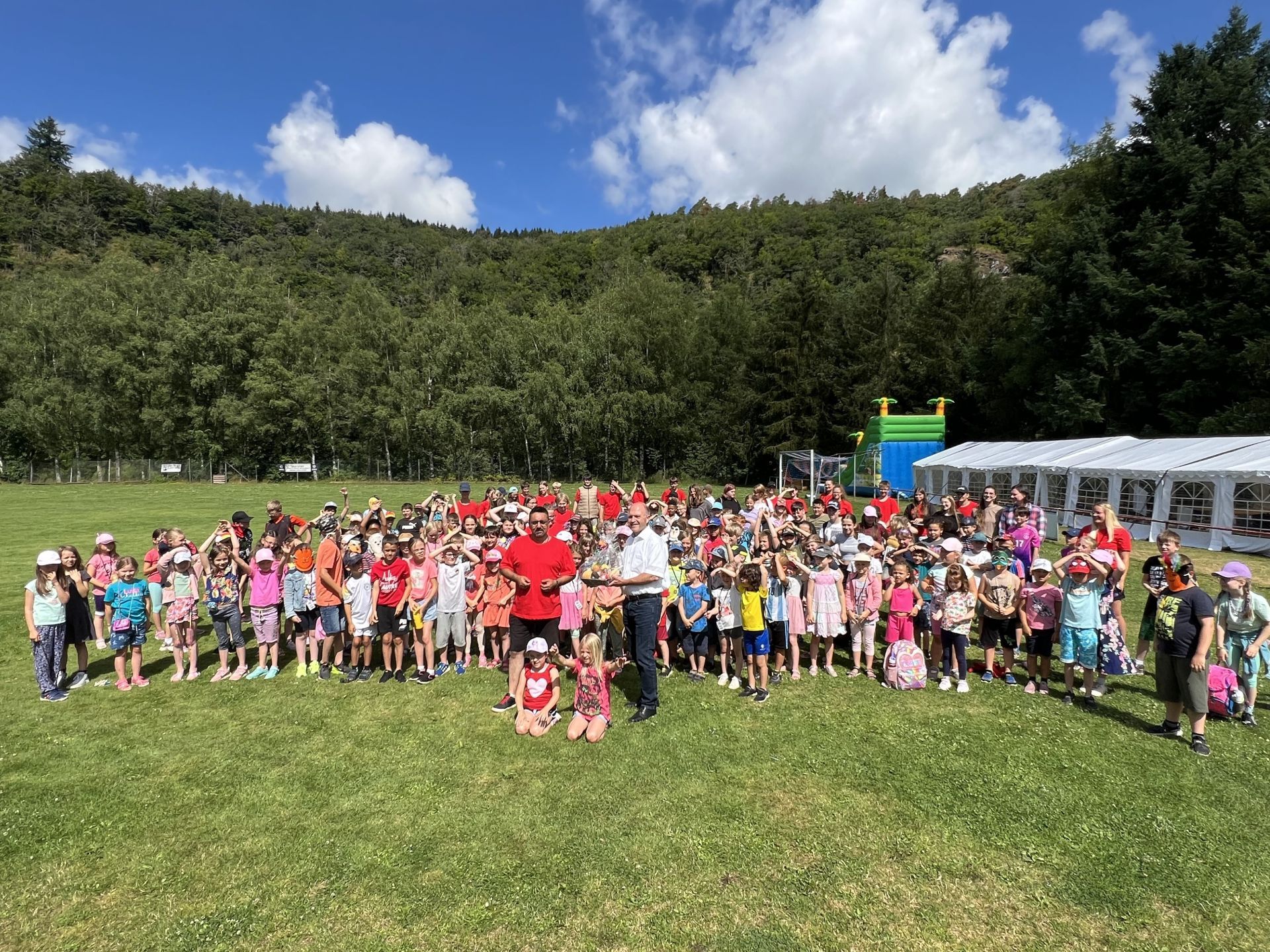 La photo montre les enfants participant à la colonie de vacances AWO avec des représentants de la ville.