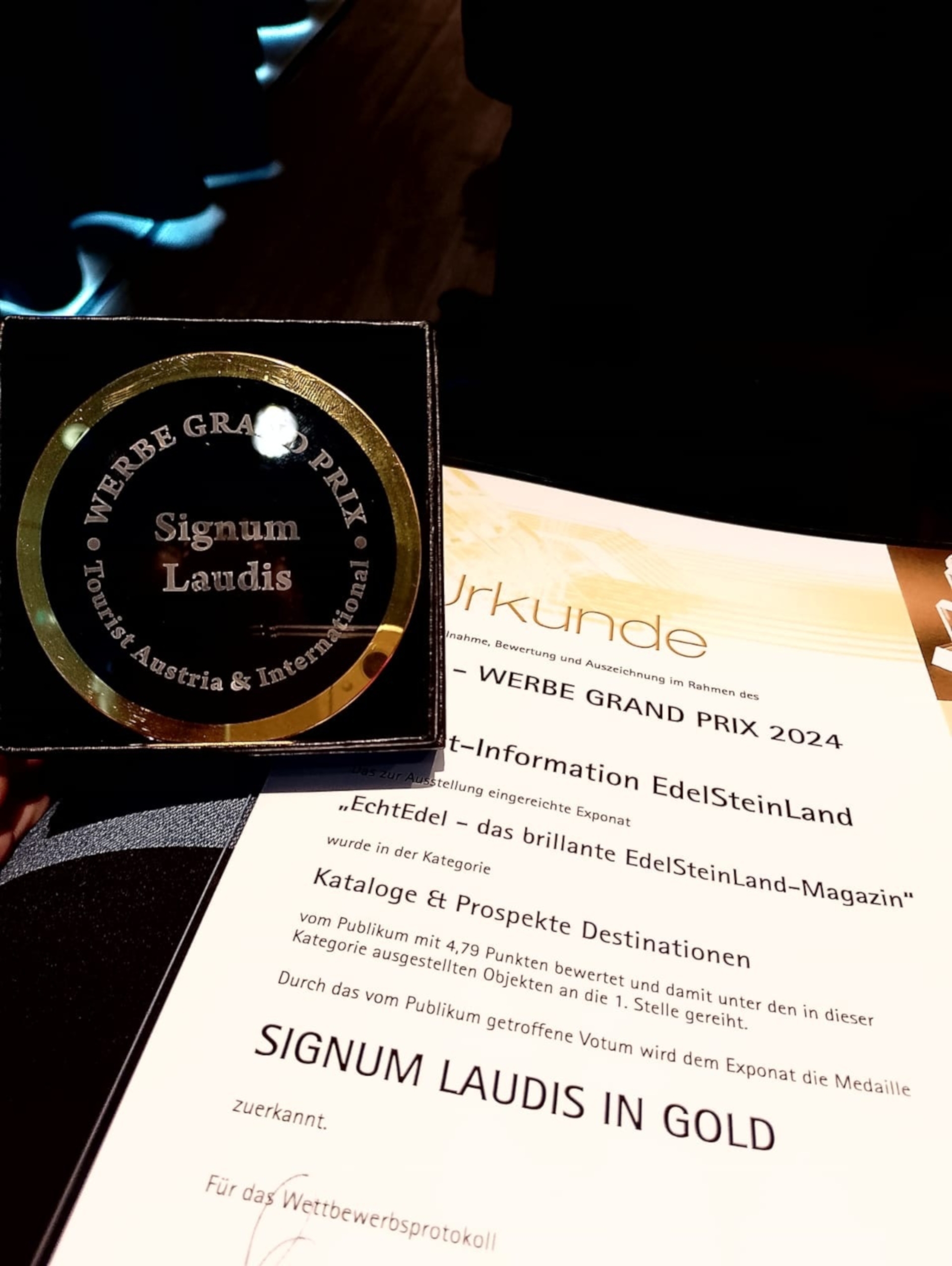 La photo montre le prix, une médaille en verre, et le certificat.