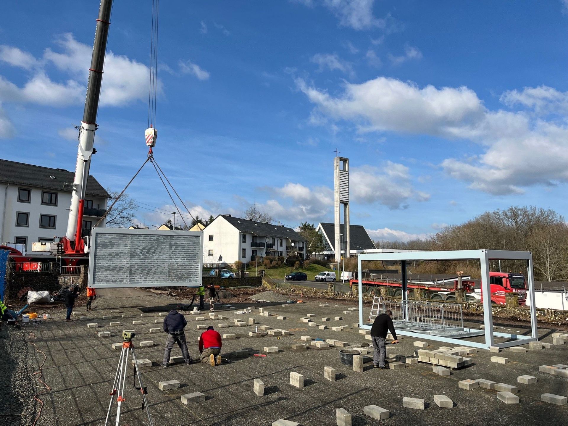 L'image montre le montage des éléments du conteneur à l'aide d'une grue.