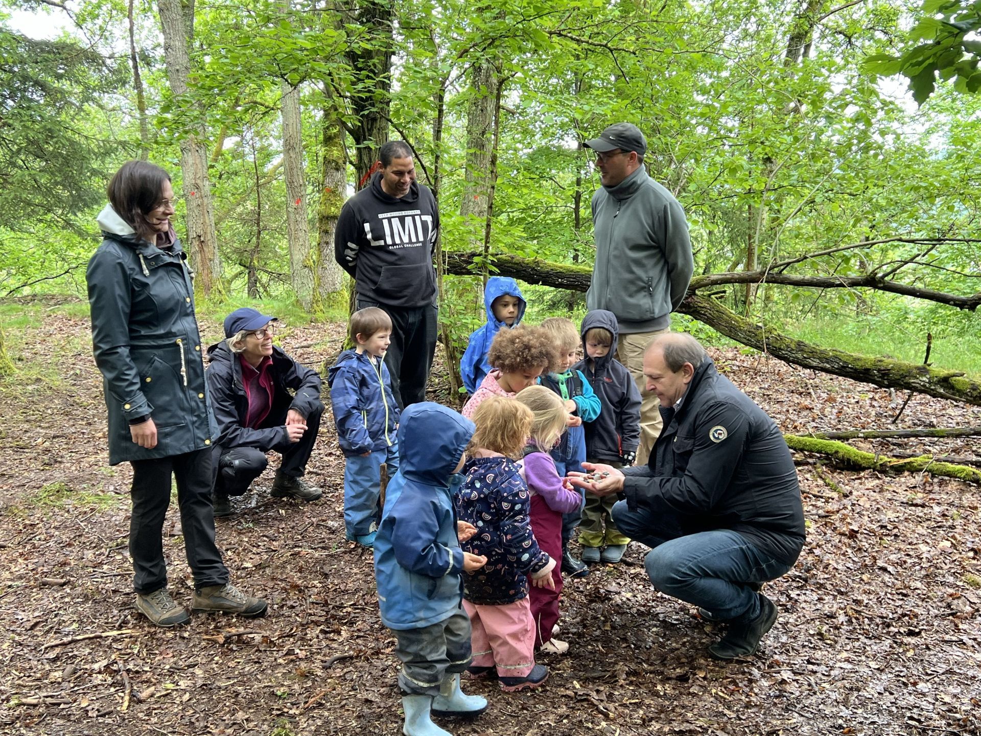 La photo montre le maire Frank Frühauf remettant des petites pierres précieuses aux enfants de la Waldkita.