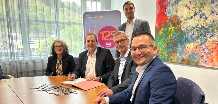 La photo montre les personnes mentionnées assises à une table ronde et regardant la caméra.