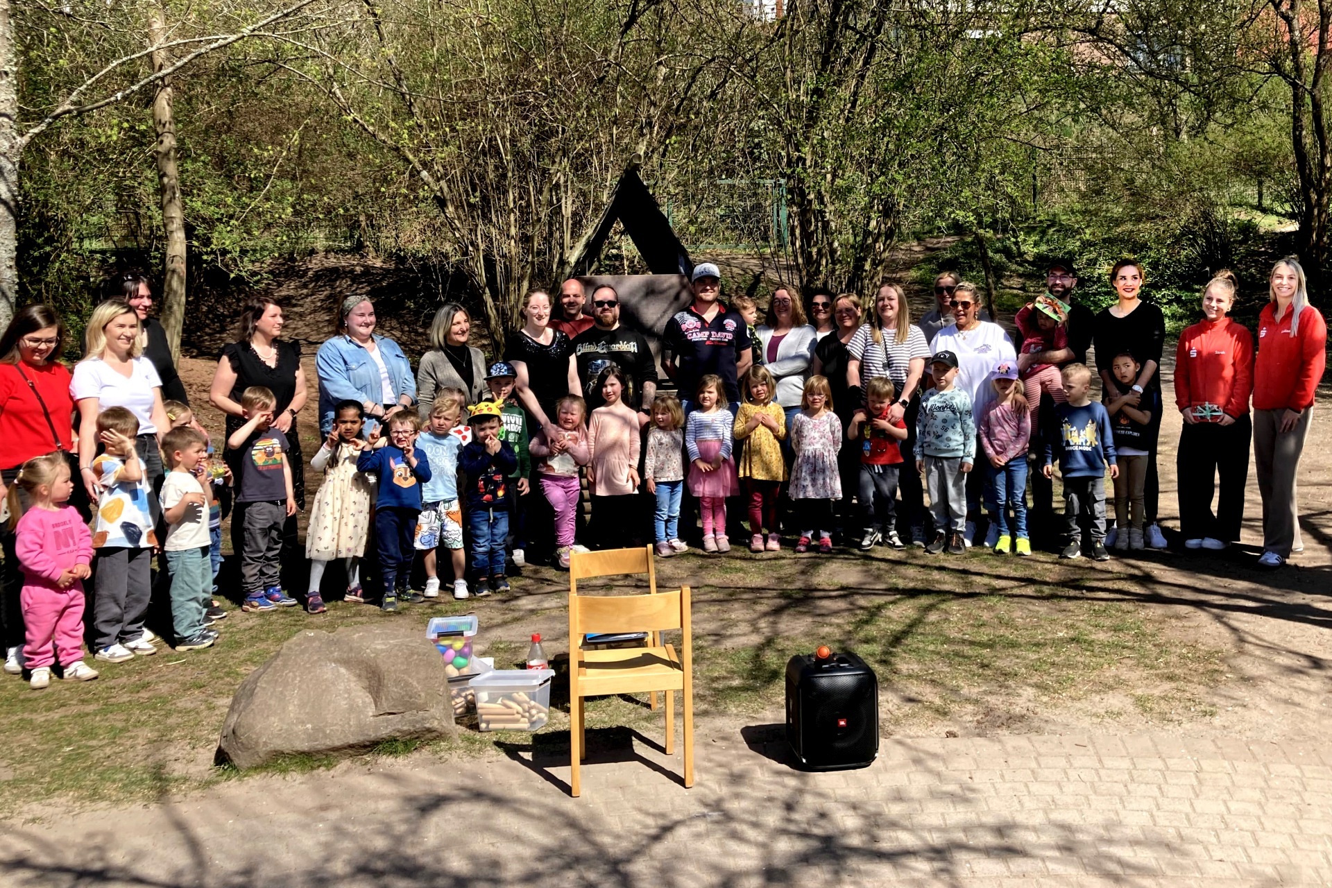 La photo montre une photo de groupe où tous les participants à la fête se tiennent côte à côte à l'extérieur.