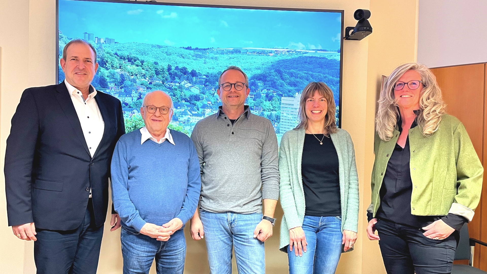 La photo montre les personnes mentionnées, debout côte à côte dans la salle de réunion du maire, faisant face à la caméra.