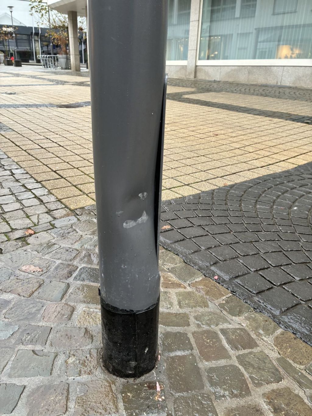 La photo montre un mât d'éclairage endommagé par un accident.