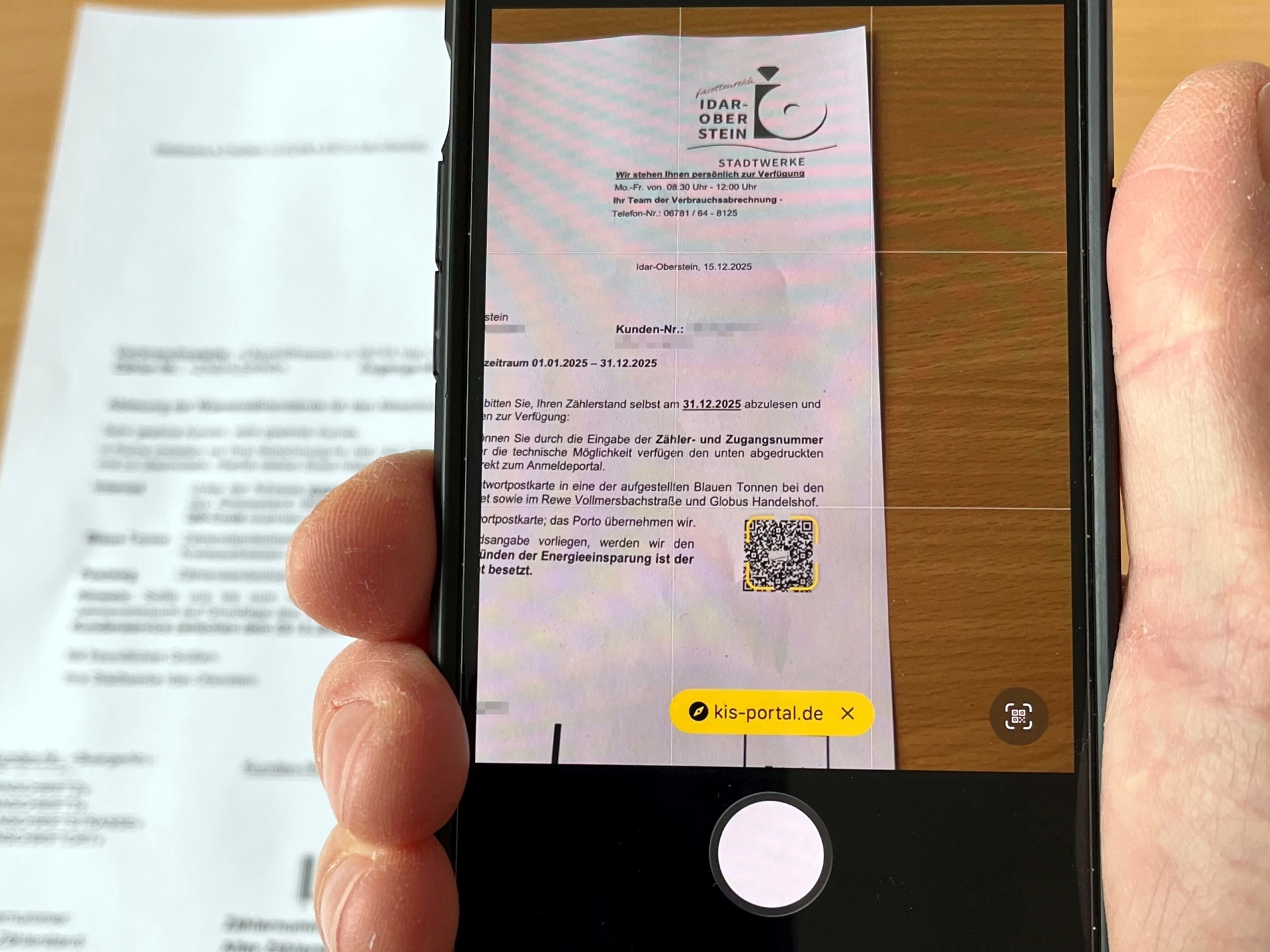 La photo montre un téléphone portable scannant le code QR sur la carte de relevé.