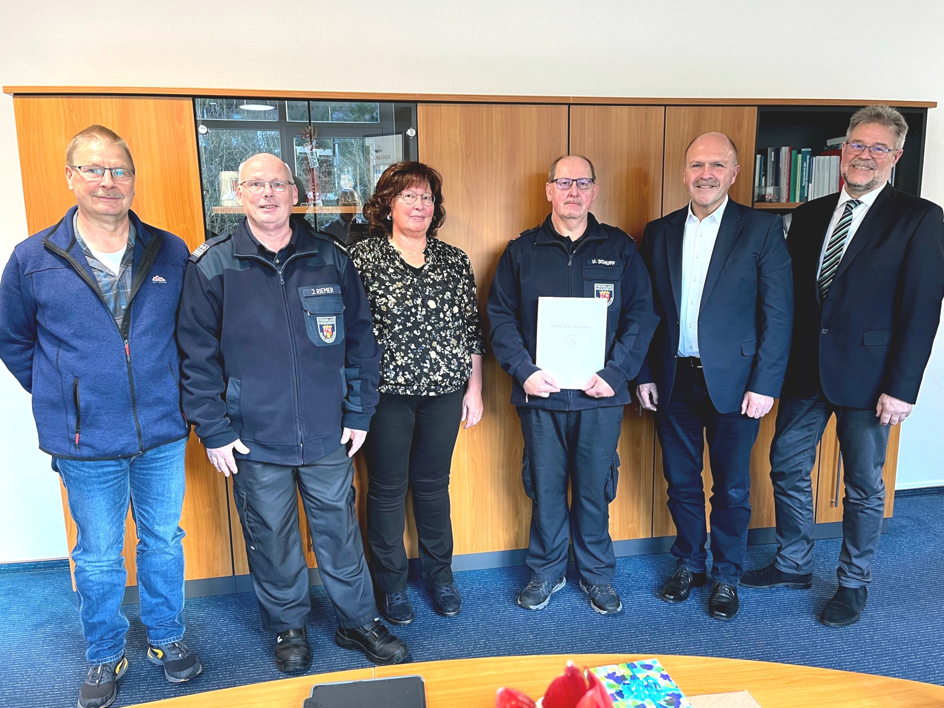La photo montre six personnes, dont Udo Schuff. Ils se tiennent côte à côte dans le bureau du maire Marx et regardent la caméra. Udo Schuff tient le certificat de remerciement dans ses mains.