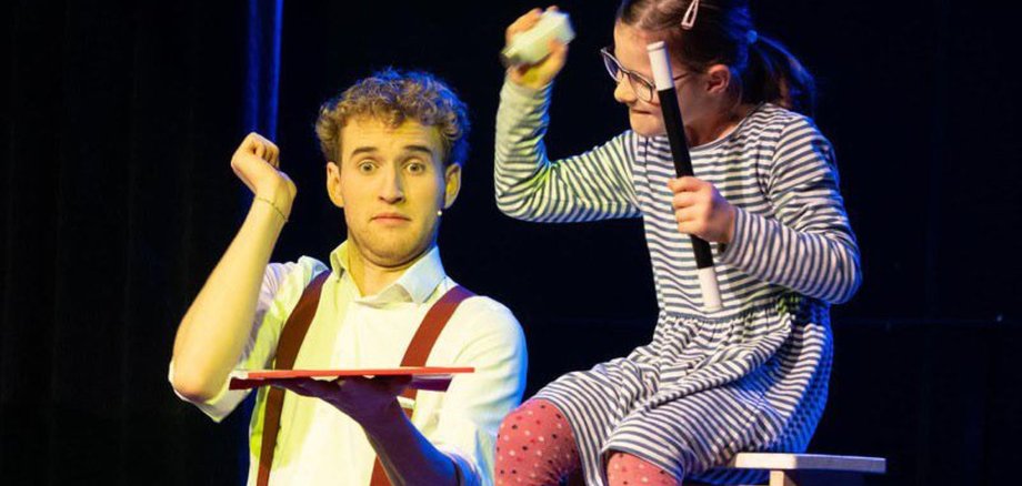 La photo montre le magicien Linus Faber lors de son spectacle sur scène dans le hall d'exposition.