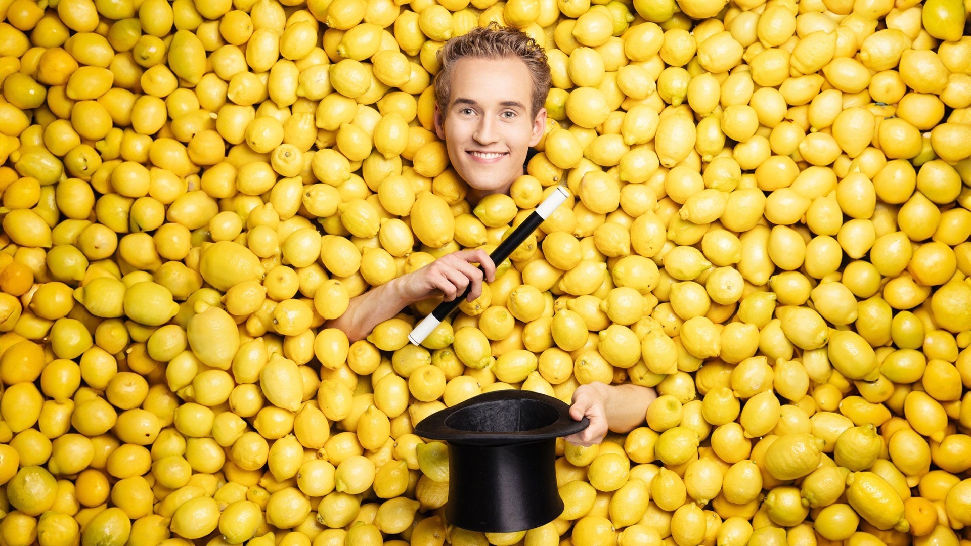 La photo montre Linus Faber avec une baguette magique et un haut-de-forme au milieu de citrons.