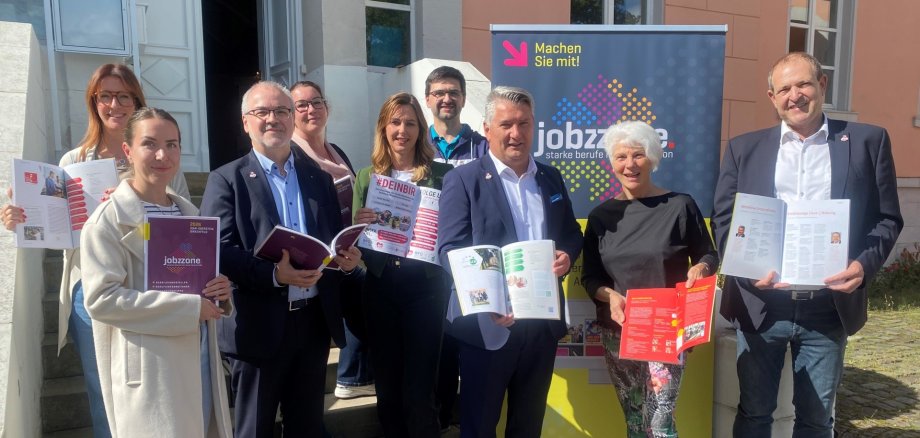 La photo montre les personnes devant l'administration du district de Birkenfeld. Elles tiennent chacune un exemplaire de "jobzzone" dans les mains.