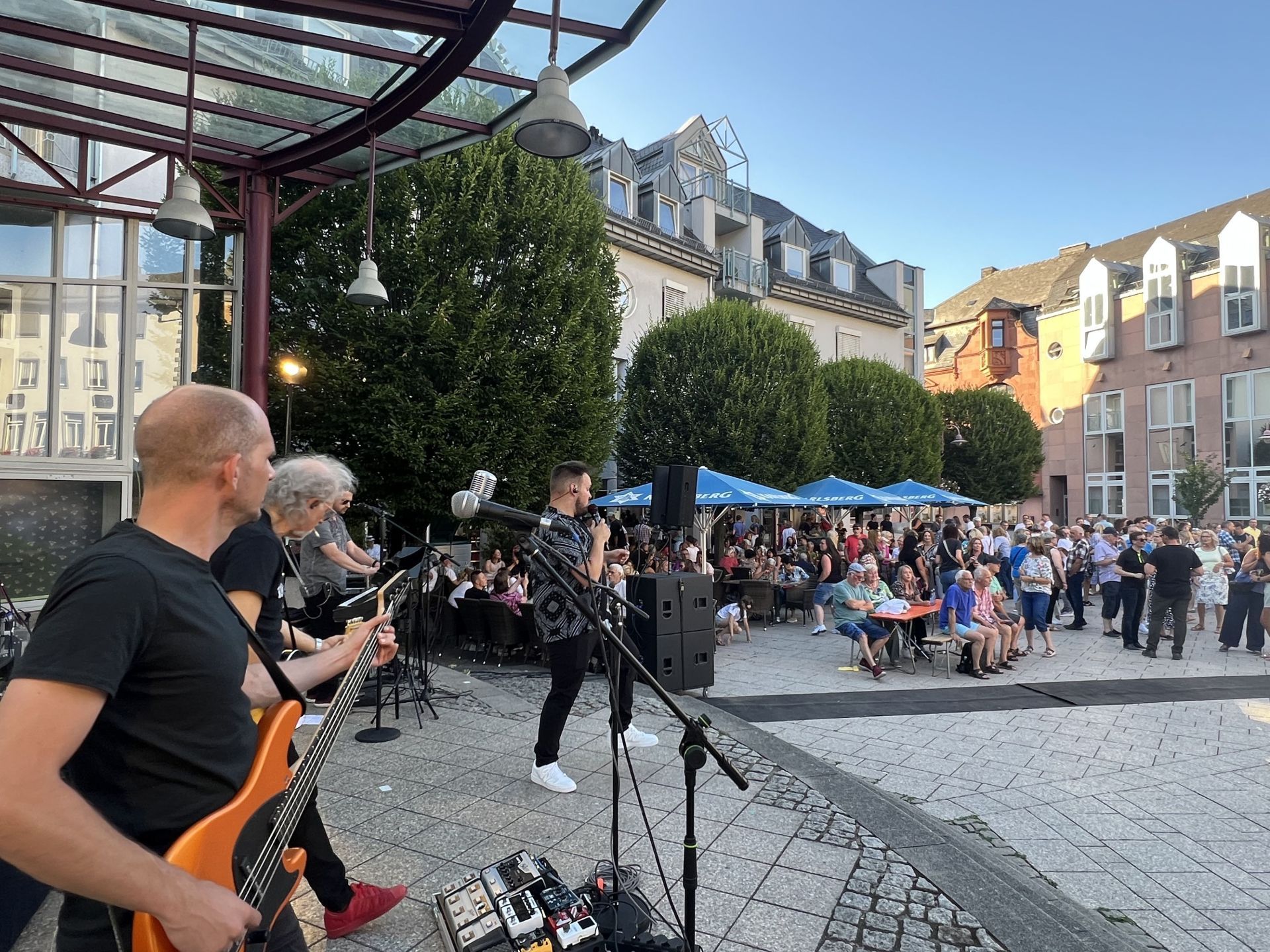 La photo montre un groupe de musique lors d'un after-work en 2025 avec de nombreuses personnes sur la place Schleifer.