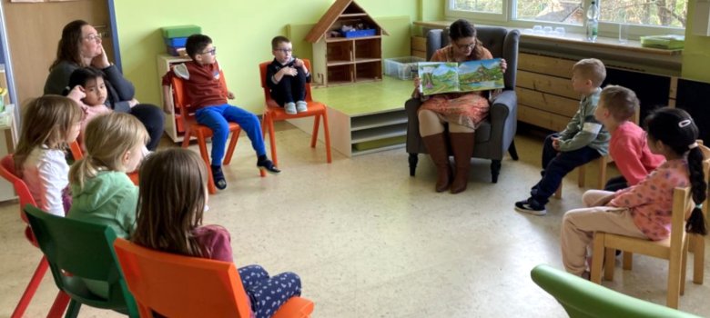 Sur la photo, les enfants sont assis en cercle avec une éducatrice et Sabrina Hoffmann.