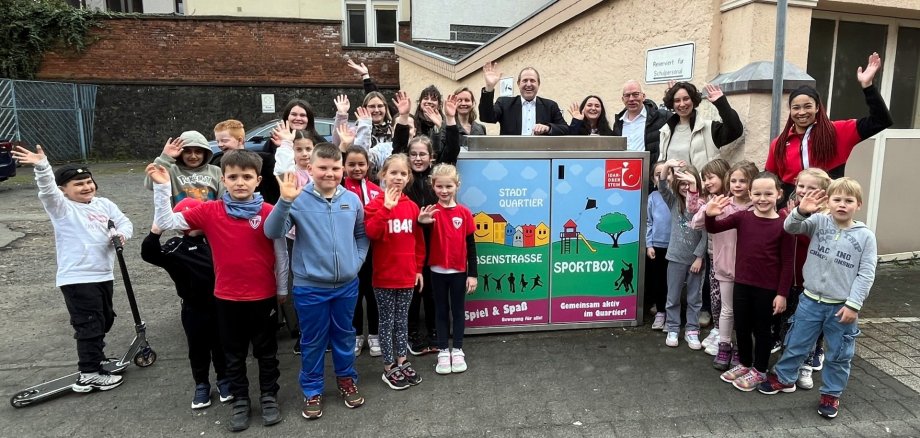 La photo montre de nombreux adultes et enfants autour de la nouvelle boîte de sport.