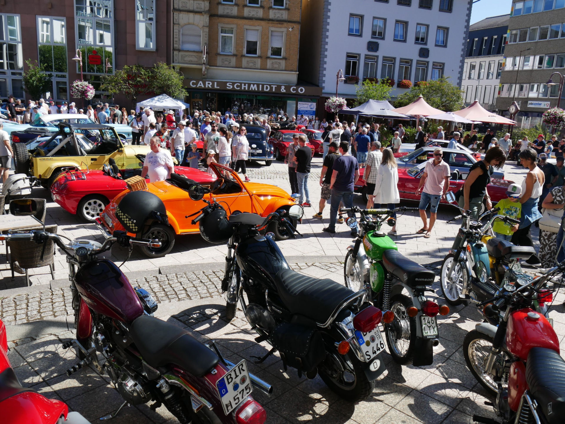 La photo montre la place Schleiferplatz, où se trouvent de nombreuses voitures anciennes et une foule de visiteurs : un événement couronné de succès.