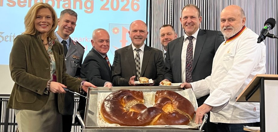 La photo montre les personnes mentionnées sur la scène de la foire d'Idar-Oberstein. Ils présentent le grand bretzel du Nouvel An.