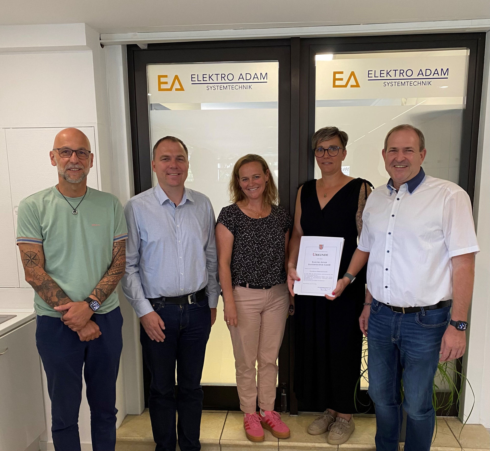 La photo montre l'équipe de direction de la société Elektro Adam en compagnie de M. Frank Frühauf, maire, et de Mme Sarah Wagner, de l'agence de développement économique.