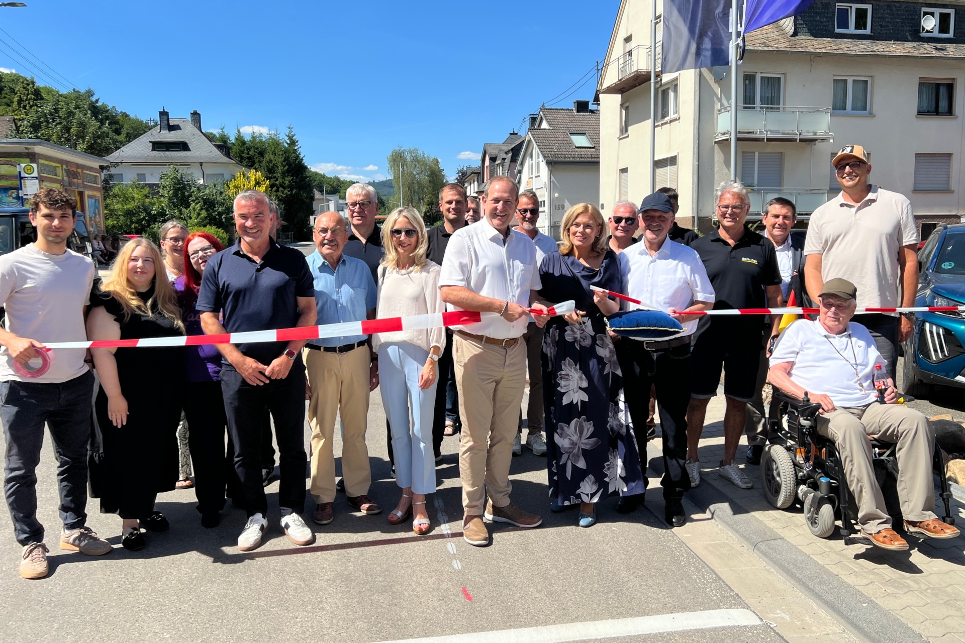 La photo montre les participants à la cérémonie d'ouverture à la circulation. Ils se tiennent derrière un ruban de signalisation et la présidente du Bundestag coupe le ruban.