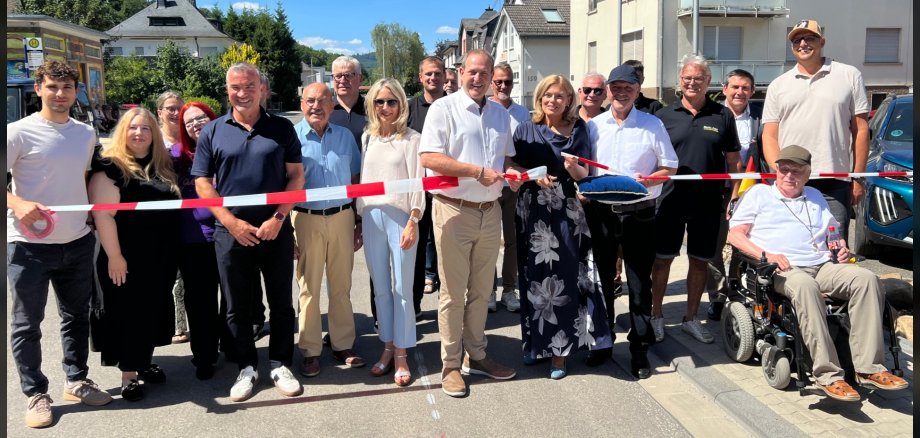 L'ouverture à la circulation de la Tiefensteiner Straße a été accueillie avec une grande joie par tous. La photo montre les participants à la cérémonie d'ouverture à la circulation. Ils se tiennent derrière un ruban de signalisation et la présidente du Bundestag coupe le ruban.