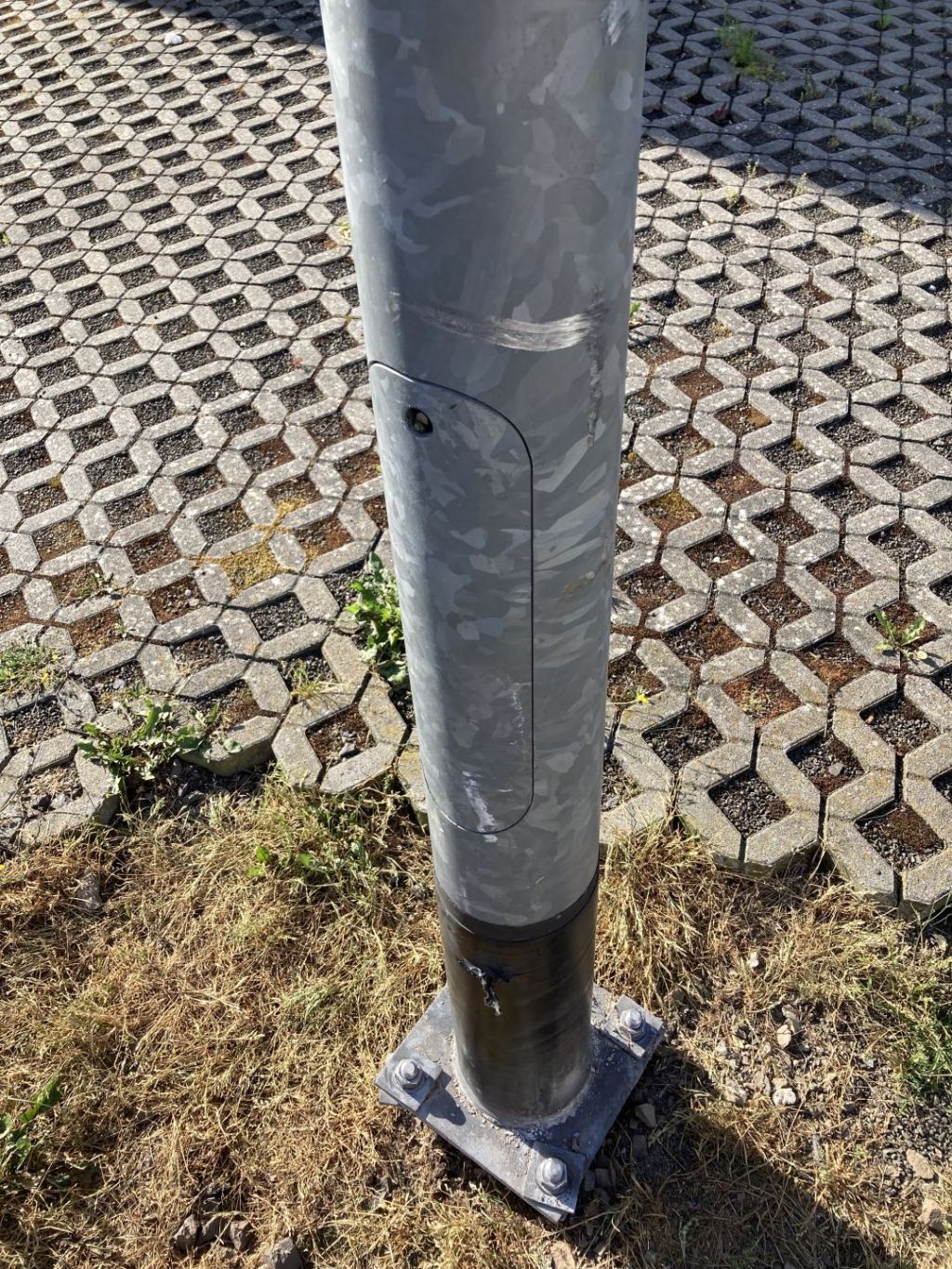 La photo montre un lampadaire qui a probablement été endommagé par un camion et qui est de travers. 