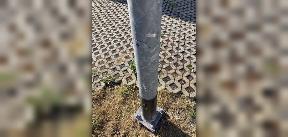 La photo montre un lampadaire qui a probablement été endommagé par un camion et qui est de travers. 