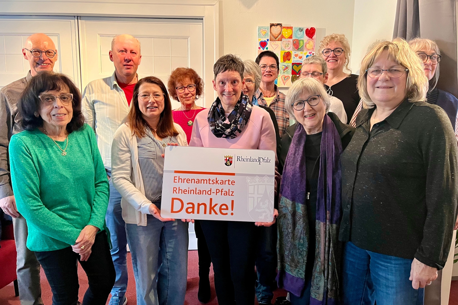 La photo montre plusieurs personnes, dont deux tiennent une carte de bénévole surdimensionnée.