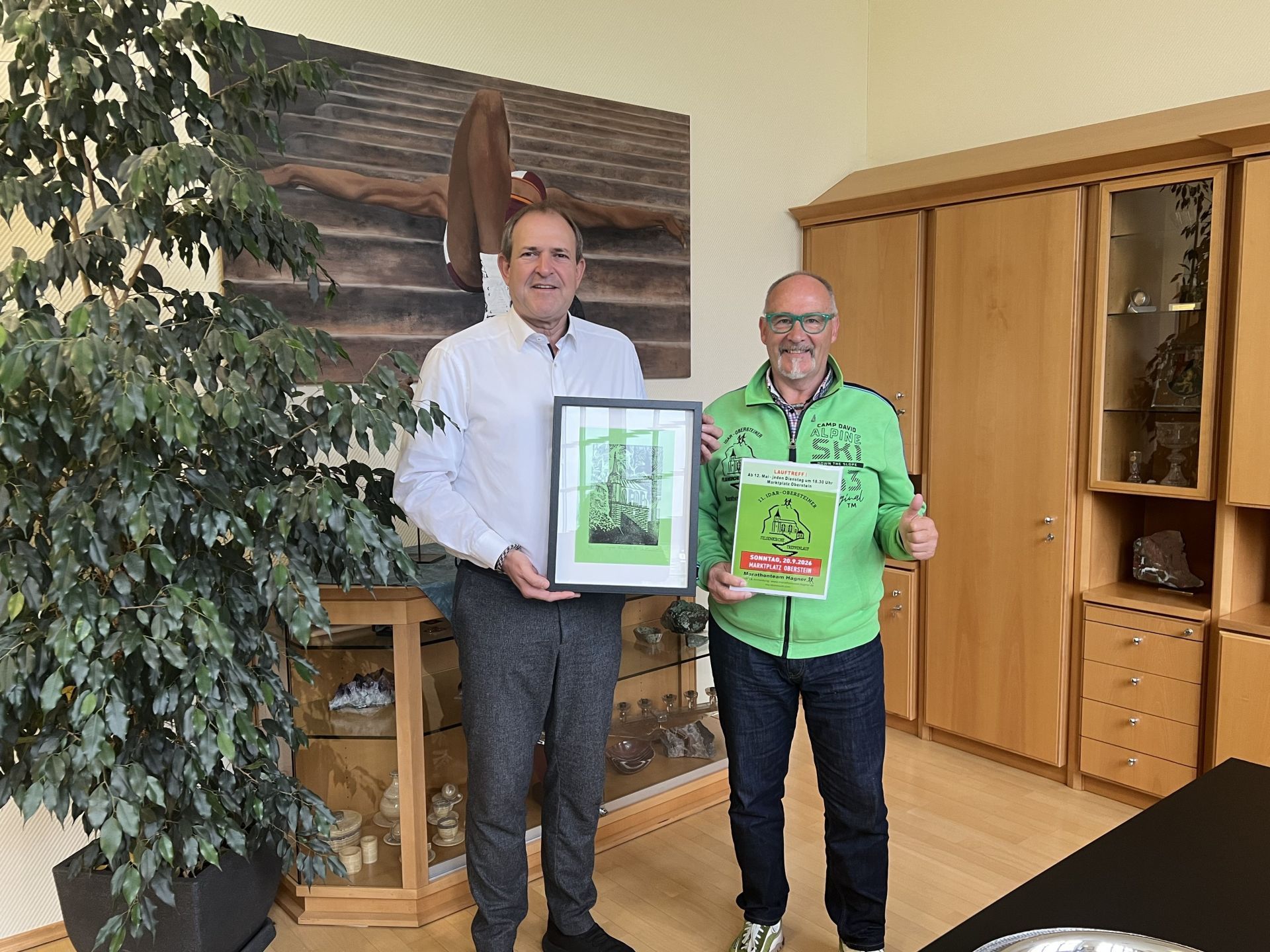 La photo montre Rainer et le maire Frank Frühauf remettant le dessin représentant l'église du Rocher.
