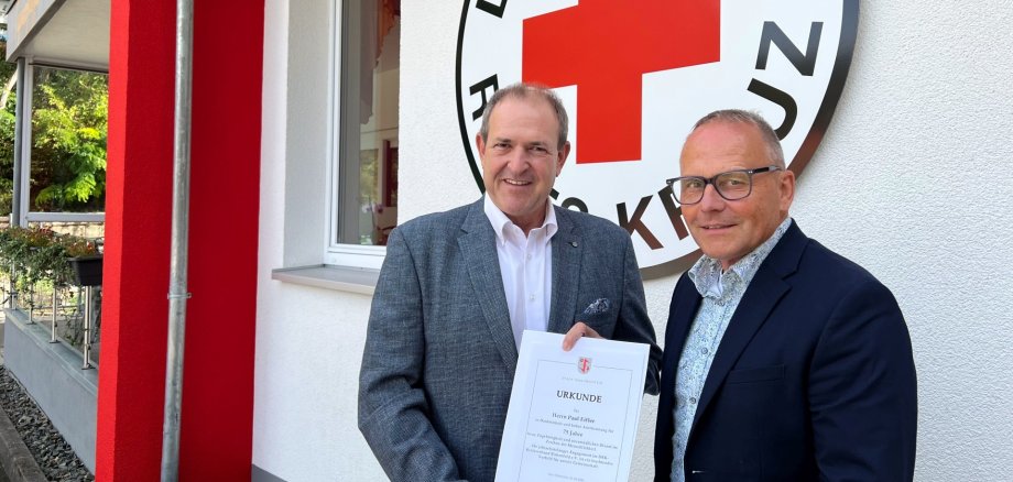 Lors de la visite des locaux de la Croix-Rouge allemande, le maire Frühauf a remis un certificat destiné à Paul Eifler au directeur général Jörg Schmitt La photo montre ces deux personnes devant le nouveau bâtiment. Le maire Frühauf remet le certificat à Jörg Schmitt.