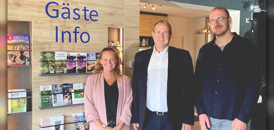 Max Stauch (à droite) a offert aux visiteurs un aperçu passionnant des coulisses de l'hôtel de montagne Kristall. La photo montre les personnes mentionnées devant un mur recouvert de brochures.