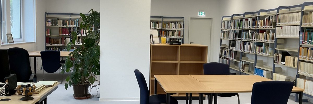 Lesesaal des Stadtarchivs Das Foto zeigt einen blick in den Lesesaal. Darin stehen Schreibtische mit Stühlen, an den Wänden sind Regale mit Archivmaterial zu sehen.
