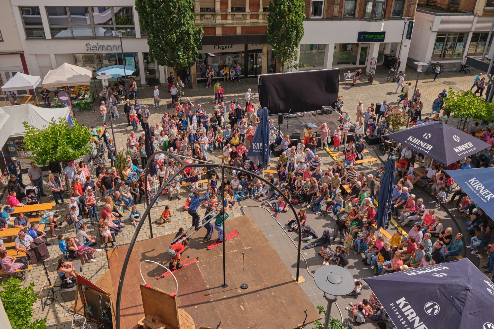 Das Foto zeigt ein Luftbild von Akrobaten auf Skiern, die vor einer großen Zuschauermenge spielen.