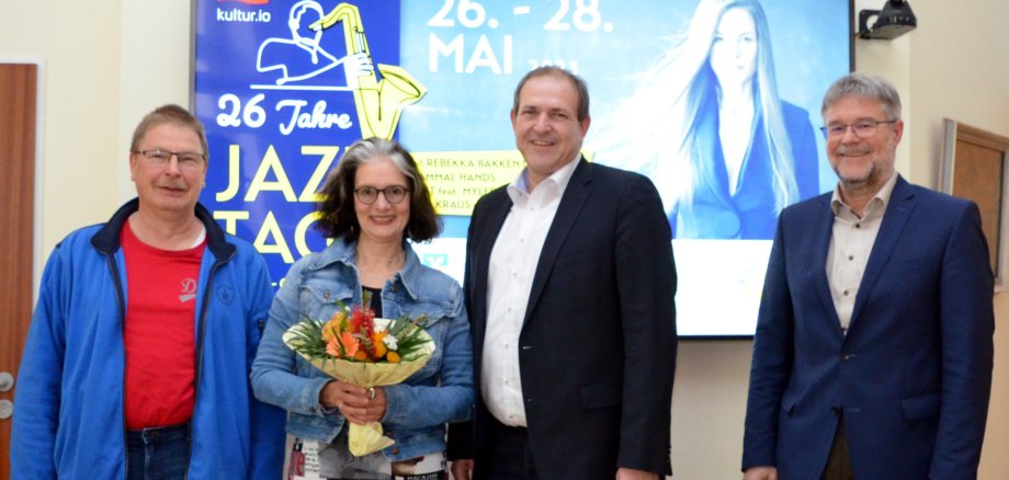 Das Foto zeigt von links nach rechts den Personalratsvertreter Volker Poes, Kulturreferentin Annette Strohm, Oberbürgermeister Frank Frühauf und den Leitenden Bürobeamten Wolfgang Petry vor einem Plakat der Jazztage Idar-Oberstein 2023.