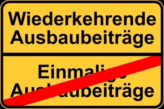 Das Foto zeigt ein stilisiertes Ortsschild. Im oberen Bereich steht Wiederkehrende Ausbaubeiträge, im unteren Bereich durchgestrichen Einmalige Ausbaubeiträge.