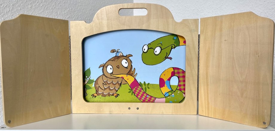 Das Foto zeigt einen Holzrahmen des Kamishibai mit einer bunten Illustration einer Eule.
