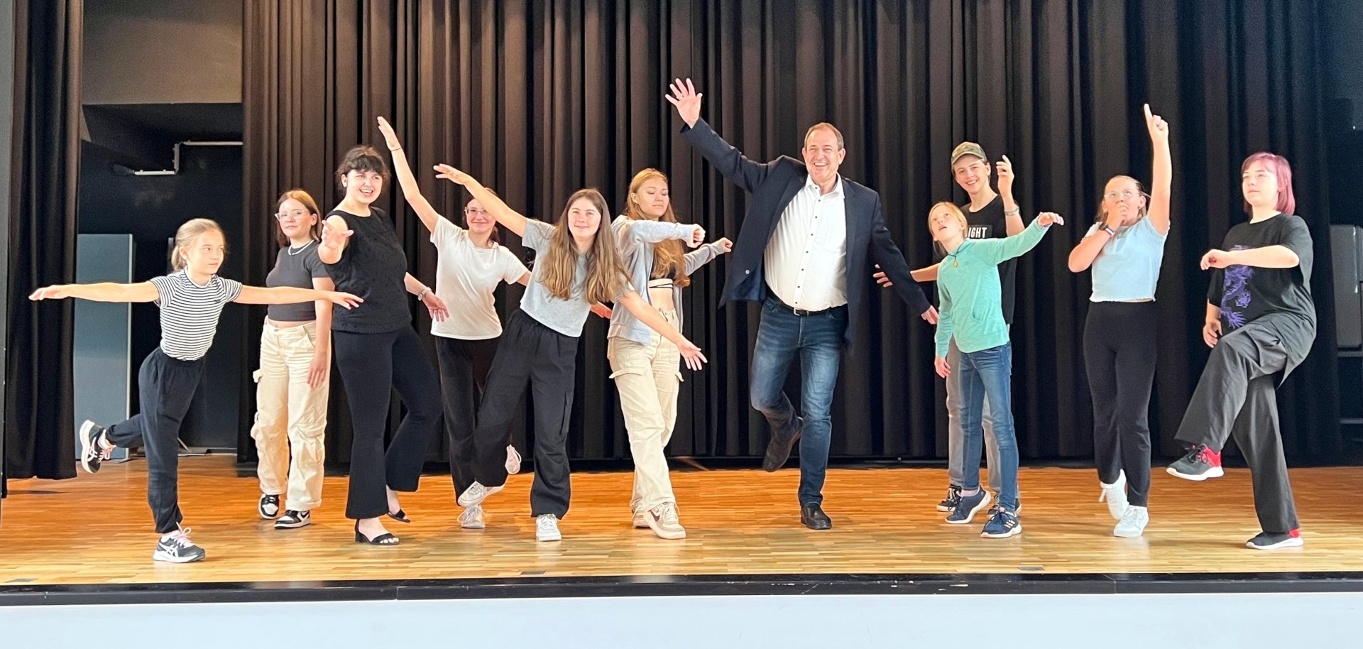 Das Foto zeigt die Teilnehmer zusammen mit Oberbürgermeister Frühauf auf der Bühne der Göttenbach-Aula. Sie stellen verschiedene Figuren dar.