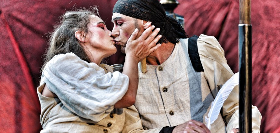Das Foto zeigt eine Schauspielerin und einen Schauspieler, die sich küssen.