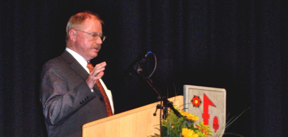 Das Foto zeigt H. Peter Brandt am Rednerpult auf der Bühne des Stadttheaters Idar-Oberstein.