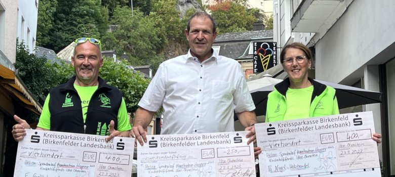 Das Foto zeigt von links Rainer Hagner, Oberbürgermeister Frank Frühauf und Ilonka Hagner. Sie stehen nebeneinander, jeder hält einen großen Spendenscheck in der Hand. Im Hintergrund ist die Felsenkirche zu sehen.