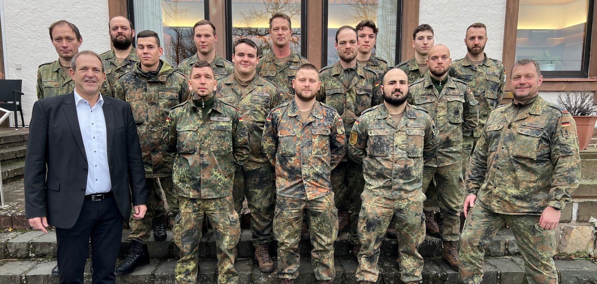Das Foto zeigt 16 Soldaten und den Oberbürgermeister. Die Personen stehen in drei Reihen auf den Stufen vor dem Kasino und blicken in die Kamera.