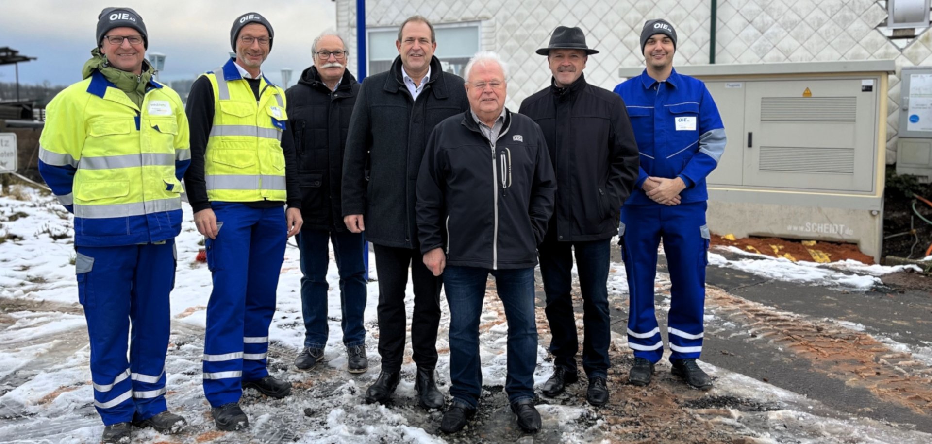 Das Foto zeigt die genannten Personen. Sie stehen nebeneinander vor der neuen Ortsnetzstation und schauen in die Kamera.