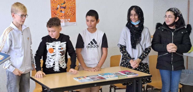 Das Foto zeigt die fünf Teilnehmerinnen und Teilnehmer des Vorlesewettbewerbs. Sie stehen nebeneinander hinter einem Tisch.