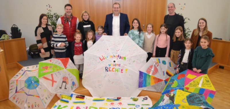 Das Foto zeigt OB Frühauf, Frank Schnadhorst, Michael Schweizer, die Lehrerinnen und Schüler. Sie stehen im Sitzungssaal hinter den aufgespannten Schirmen und dem großen Transparent und blicken in die Kamera. 