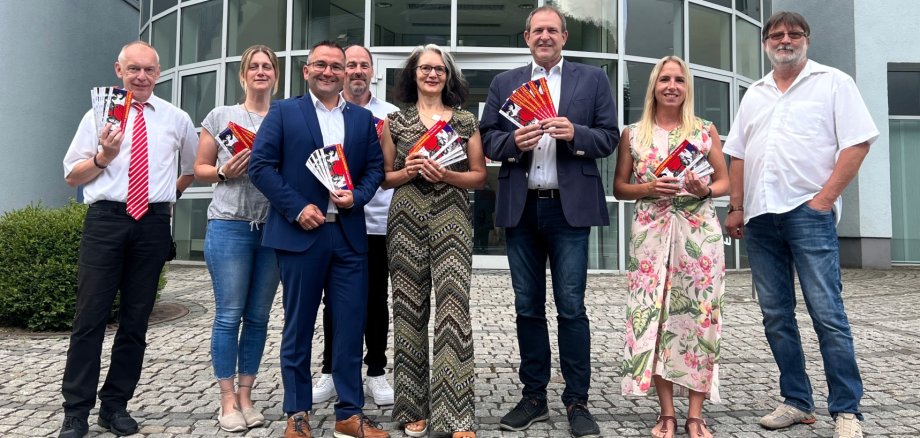 Das Foto zeigt mehrere Personen, die mit Flyern des Theatersommers vor dem Firmengebäude der OIE AG stehen. 
